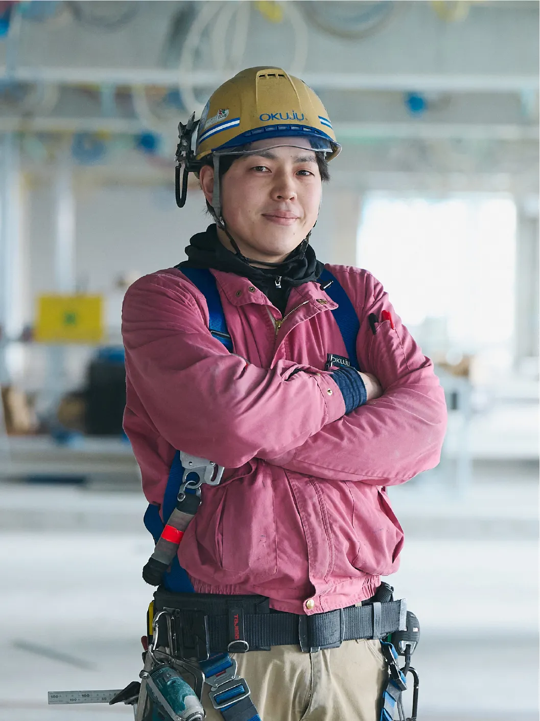 腕を組んで立つ作業服を着た男性