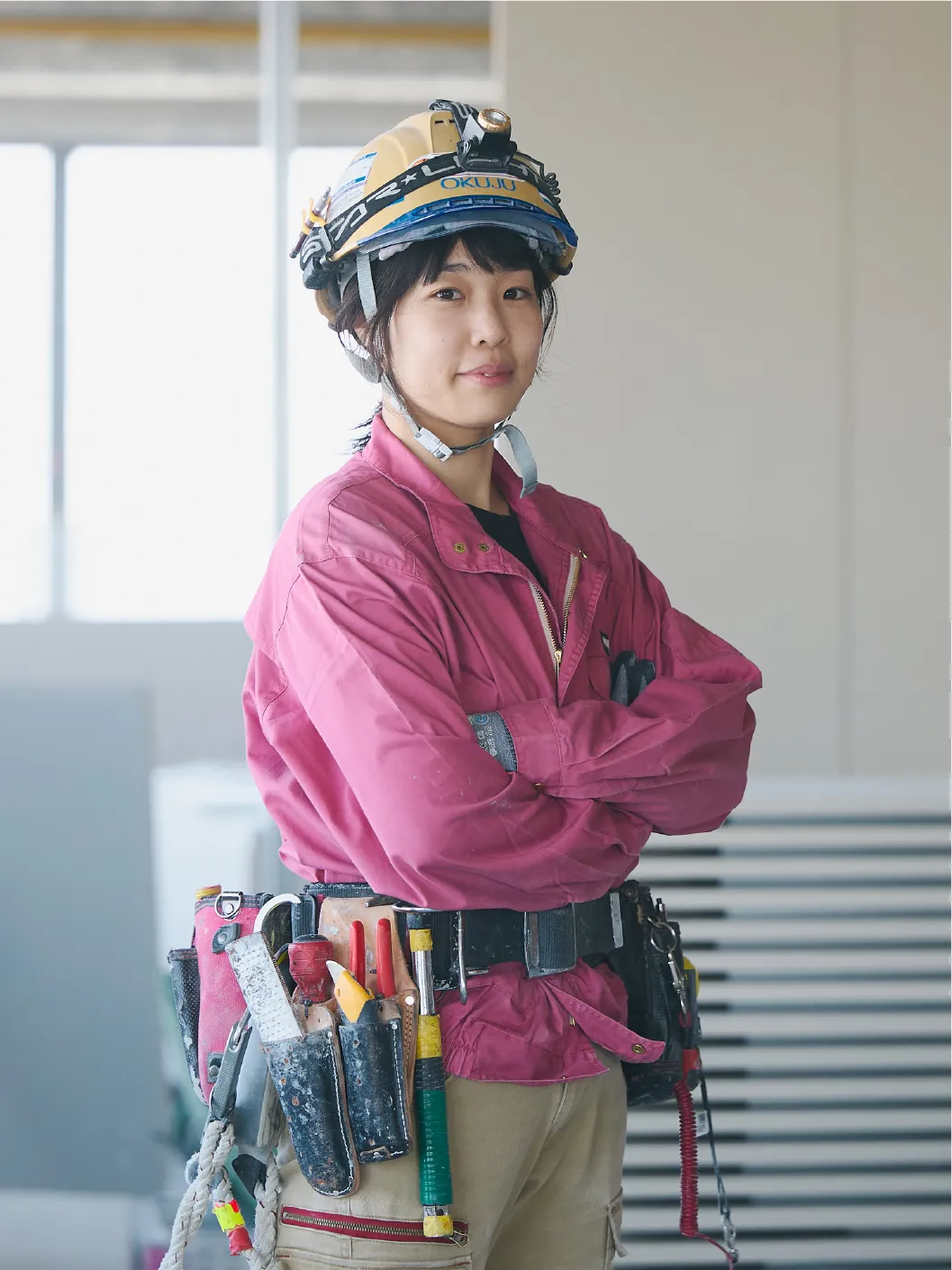 腕を組んで立つ作業服を着た女性