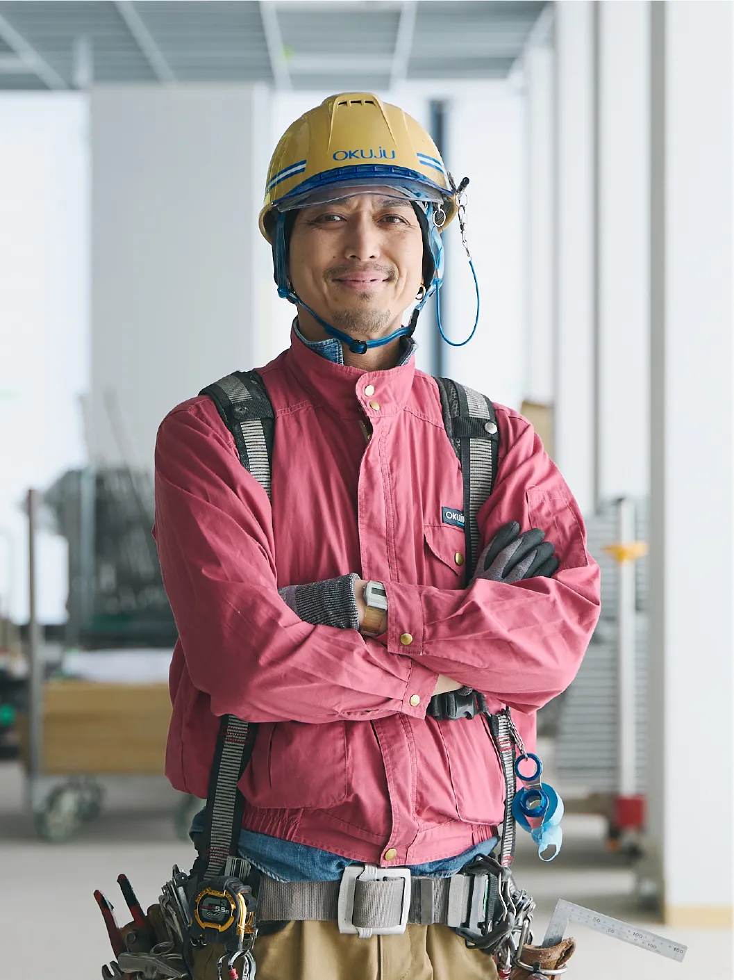 腕を組んで立つ作業服を着た男性
