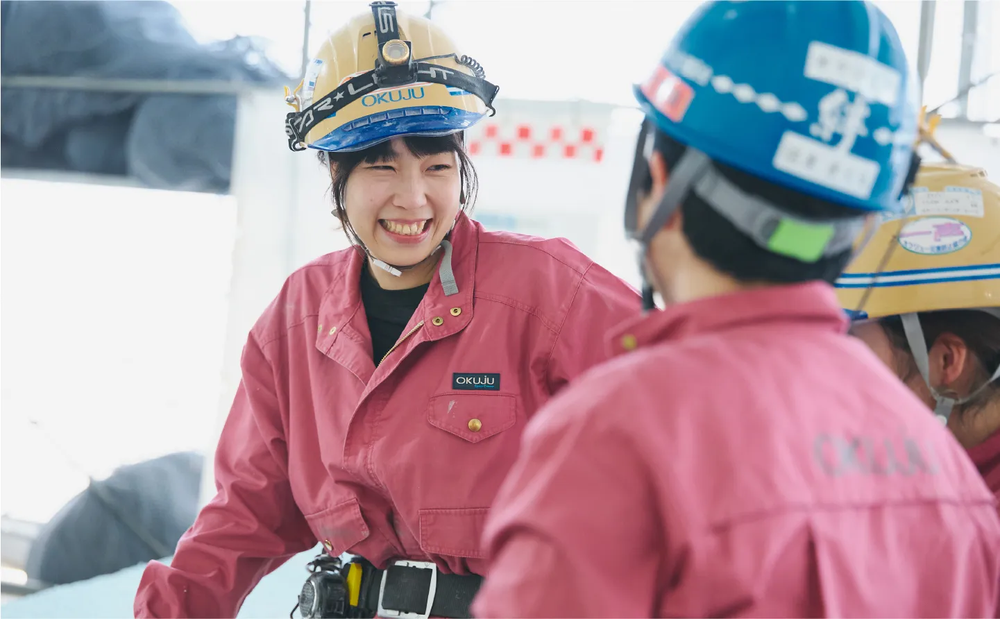 作業着を着た男性が天井のパイプを掴んで作業をする様子