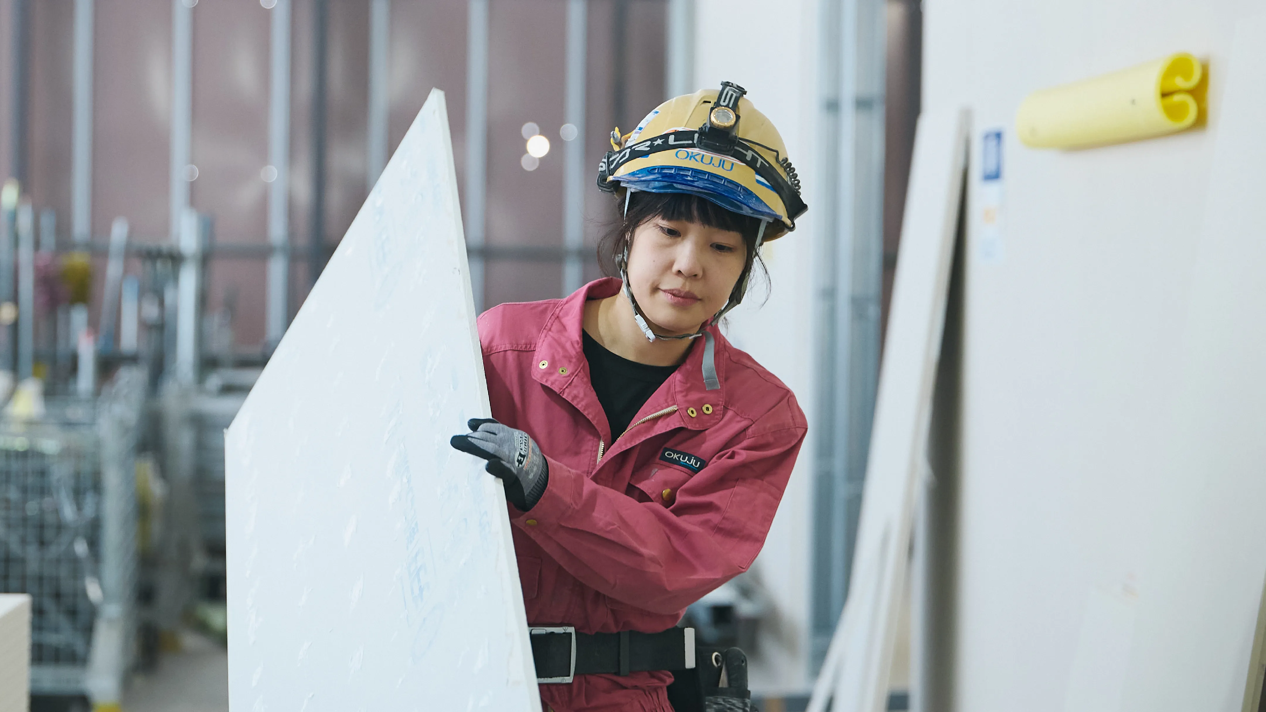 板を運ぶ作業服を着た女性